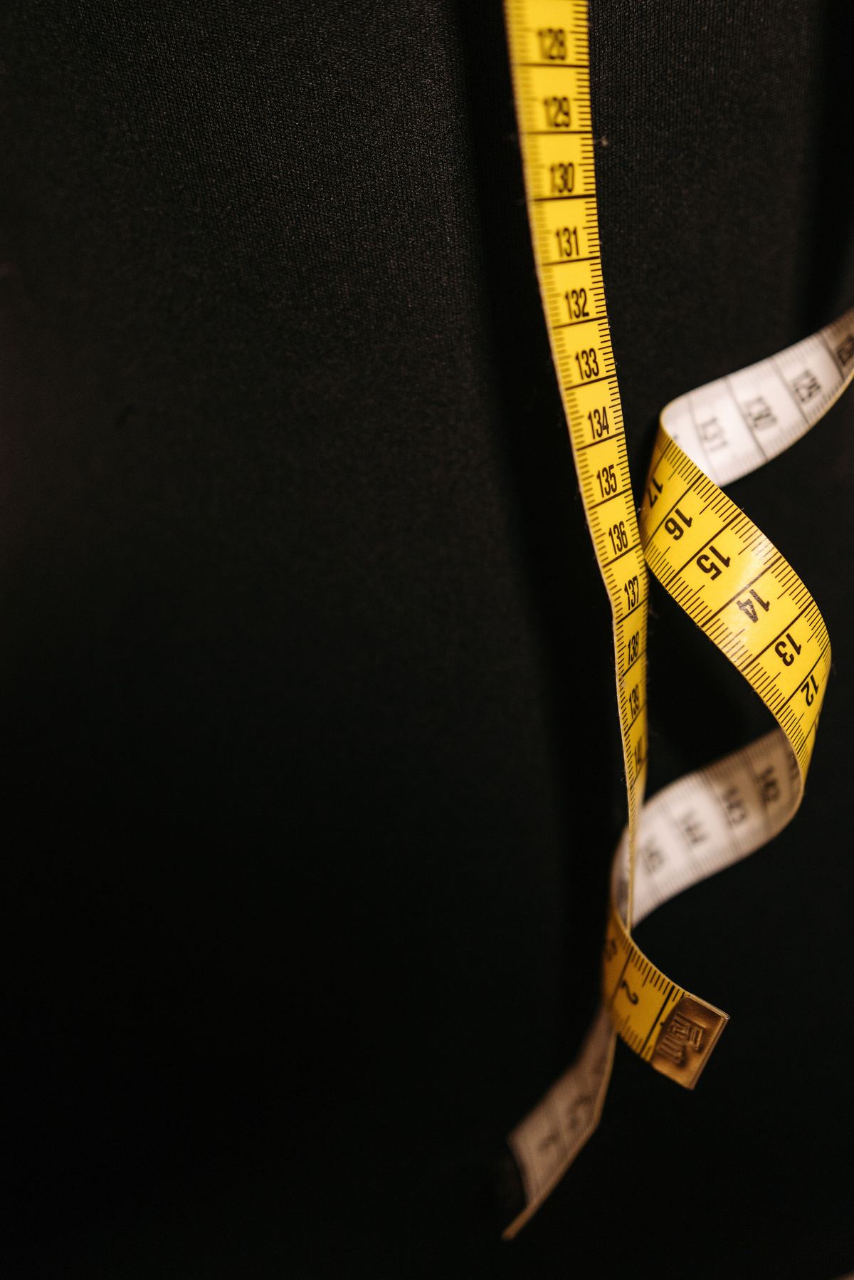 A tailor's measuring tape hanging on dark fabric