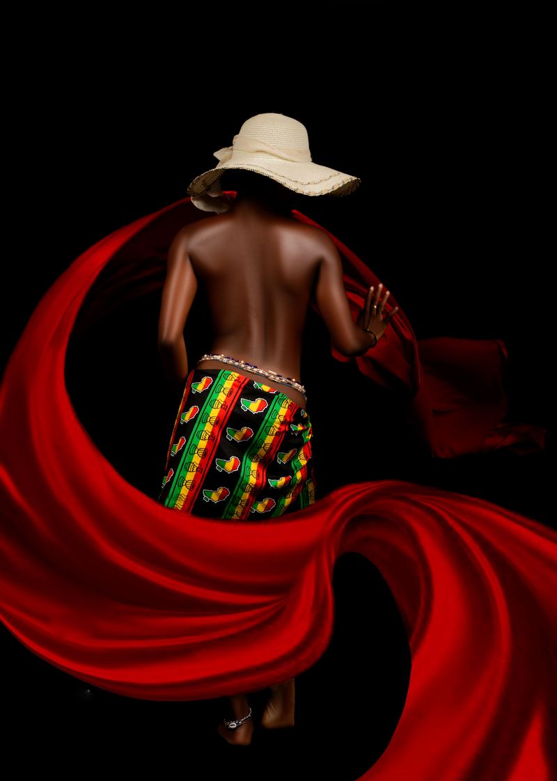 Red silk fabric swirling in motion around a wrap skirt with African patterns